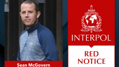 Interpol A composite image showing a picture of Sean McGovern - a man with short brown hair wearing a blue and grey zip up hoodie - on the left, on the right is the Interpol logo in white against a red background with Red Notice written underneath in a red font against a white background. His name 9Sean McGovern' is written in white with a red background underneath him