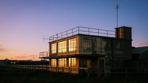 The former Jurby air traffic control centre, which is block military looking building, at sunset.