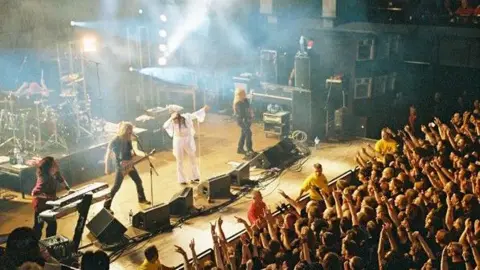 Supplied A band on stage in front of a crowd.