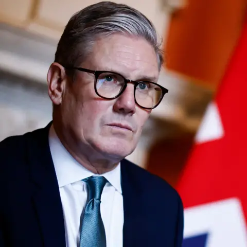 Getty Images Sir Keir Starmer looking pensive with out-of-focus Union Jack to his right 