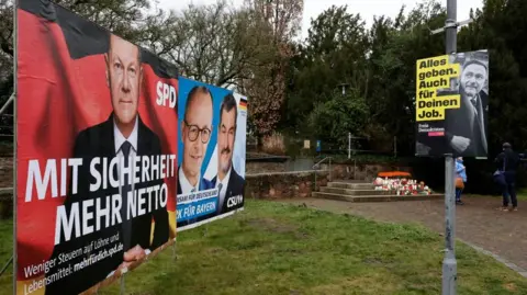 RONALD WITTEK/EPA-EFE/REX/Shutterstock Election posters for Germany's chancellor and the main frontrunner in the vote can be seen a few metres from flower and candles in the park.