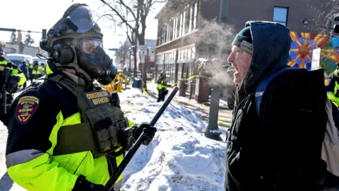 A man speaks to a Minnesota Department of Natural Resources Conservation Officer as demonstrators gather near the site of where state and local authorities say a man was shot and killed by federal agents earlier in the morning in Minneapolis, Minnesota, on January 24, 2026