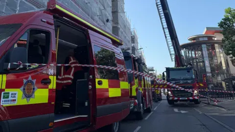 Jersey Fire and Rescue A picture of a number of fire vehicles parked outside the flats. There is red and white tape, with red and yellow fire trucks.