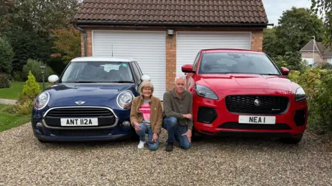 Neal Bircher Neal Bircher next to an 'NEA 1' plate on his red car, and his mother Anthea who has an 'ANT 112A' plate on her blue  Mini