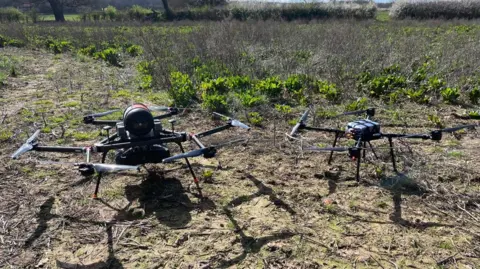 Two drones on the ground in a field.