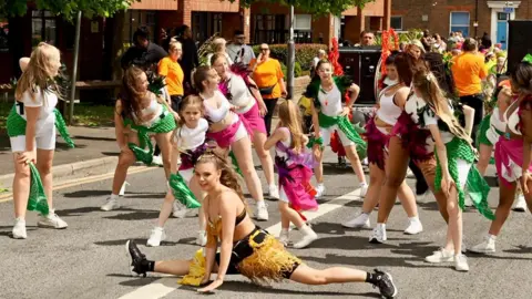 Stephen Huntley/BBC A parade of children in costume dancing on the street as part of Luton Carnival