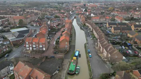 An aerial shot of Beverley Beck, with boats on the canal and a development of newer housing around it.