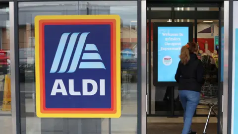 REUTERS/Phil Noble A shopper walks inside an Aldi supermarket