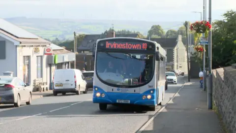 An Ulsterbus travelling towards Irvinestown driving through a rural village