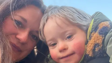 A selfie of Charli, a womanwith long brown hair, and a young blonde boy, they both smile brightly.