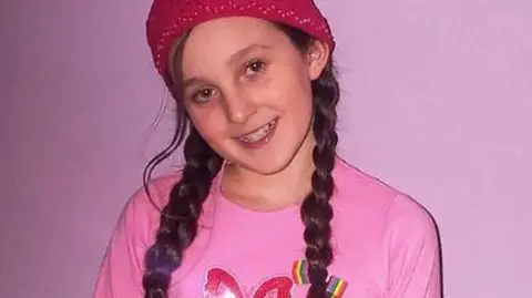 Rosie's Rainbow Fund Rosie Mayling in a pink t-shirt and a pink beanie hat looking at the camera
