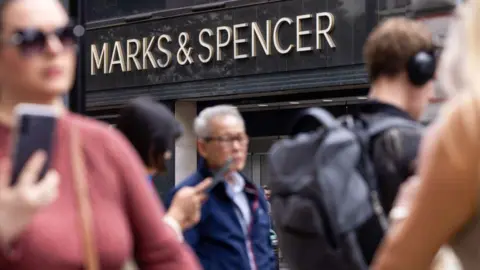 Getty Images People walking in front of Marks and Spencer store front.