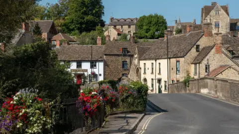 Floral decoration over St Johns bridge, with a line of homes in the background.
