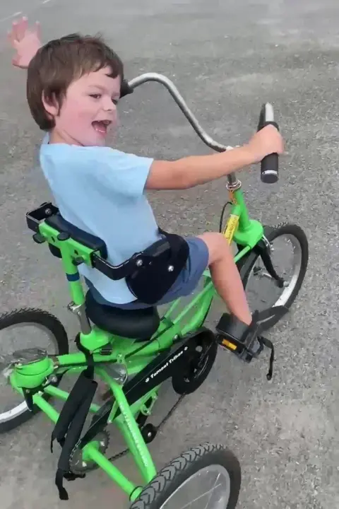 Tammy McDaid Tate is looking back and smiling while riding a tricycle.