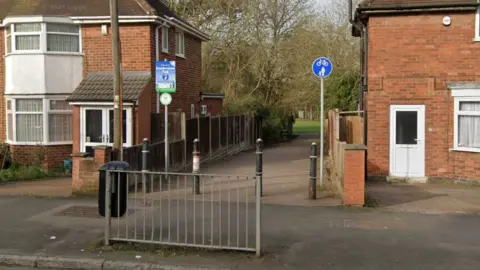 An alleyway is pictured with a park in the background