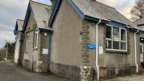 Fowey Community Hospital, which is agrey rendered building with blue fascia and downpipes.