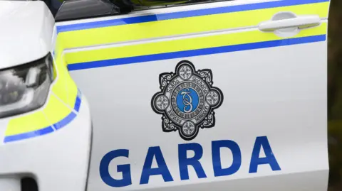 A garda car door. It is open and has the official badge on the side. 