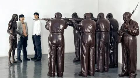 Supplied "Execution of Christ" depicts a sculpture comprising a squad of Mao-like figures holding Jesus Christ at gunpoint