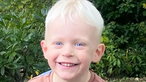 Family Handout Headshout of Oscar Neillings. He is three-years-old and has blonde hair and blue eyes. He is smiling for the camera.