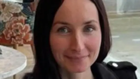 Police Scotland A woman with dark hair and blue eyes. She is smiling at the camera and wearing a black jacket.