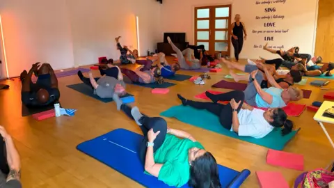 People lying on exercise mats on the floor during a session.