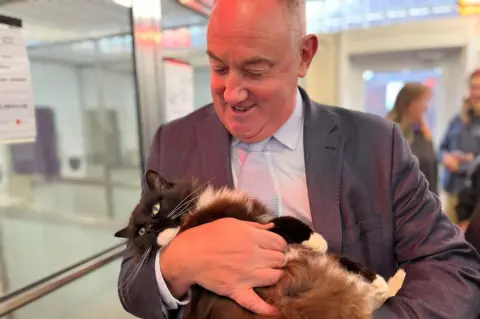 Scottish government housing minister Paul McLennan holding a cat during a visit to a Scottish SPCA shelter in Edinburgh