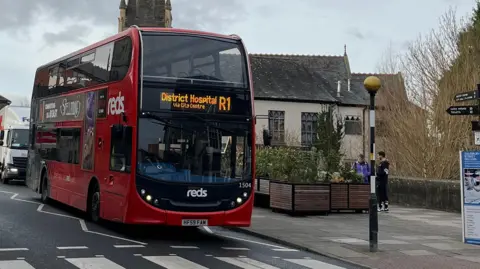 A double-decker Salisbury Reds bus approaches a zebra crossing in Salisbury.