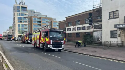 BBC/George Carden A series of fire engines on a road outside a building. 