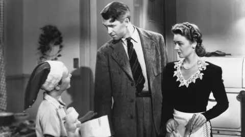 Screen Archives/Getty Images James Stewart, Donna Reed and Larry Sims in a scene in the 1946 Frank Capra film 'It's a Wonderful Life'. (Photo by Screen Archives/Getty Images)