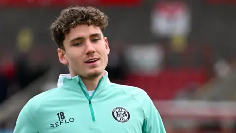 Isaac Moore during a warm-up with Forest Green Rovers. He is wearing a turquoise club training top