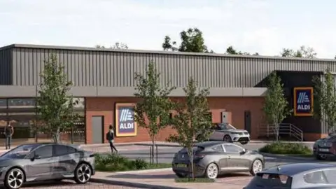 An artist's impression of the new Aldi supermarket shows the building and a car park in front of the store, with vehicles parked in front of it and trees planted around the area.