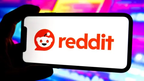 Getty Images Un teléfono sobre un fondo violeta brillante con una pantalla blanca y el logotipo naranja de Reddit.