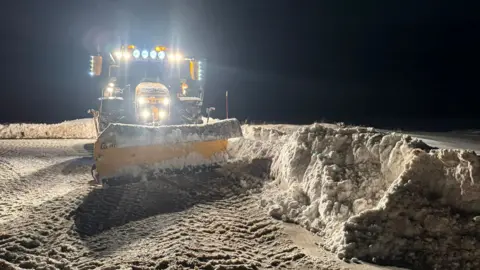 Bear Scotland A tractor with a snow plough working in darkness to clear banks of snow