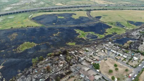 LFB The village of Wennington from above, with large swathes of grassland burnt and blackened.