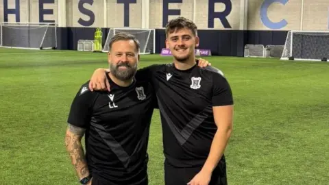 University of Chichester Two men stand next to each other. They each have their arms around the others shoulder 