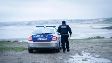 PA Media French Police officer looks out over a beach near Wimereux in France believed to be used by migrants trying to get to the UK, November 25th 2021