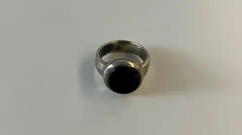 Metropolitan Police A close up image of a tarnished looking silver ring with a big, black, flat stone in the centre.