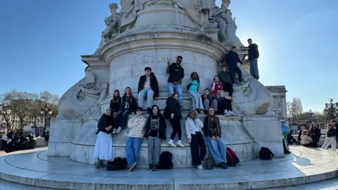 The Way Youth Zone A group of teenagers stand next to an on a large white monument
