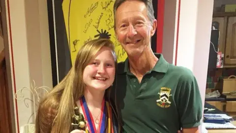 Isla Bayliss/JustGiving A woman on the left with long hair is smiling and she is next to a man wearing a green top on the right.