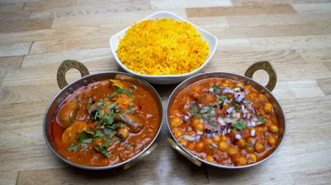 Desi Yew Tree Three bowls of food are sat on a table. One is yellow rice, two are curry dishes