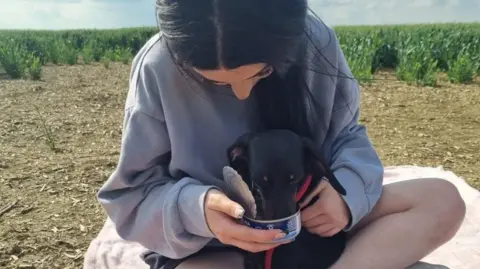 Family photo Mila eating out of tin while being held by her owner