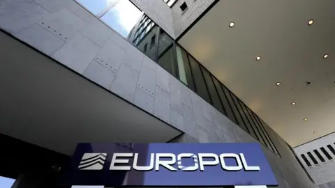 EPA The exterior of the Europol building in the Hague - a dark blue sign with the Europol name in white text stands below a tall concrete building
