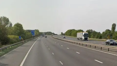 Google A picture of the M18 motorway showing both sides of the motorway surrounded by trees and greenary 