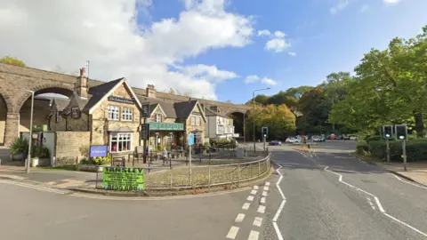 A pub between a road and some railway arches