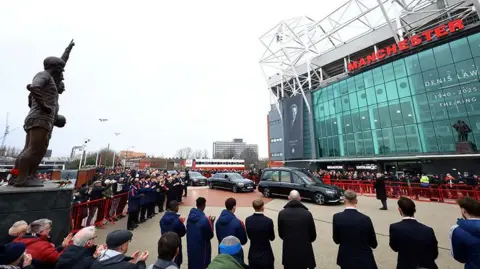 Thousands of fans clapping at Manchester United's Old Trafford as Denis Law's funeral cortege arrives