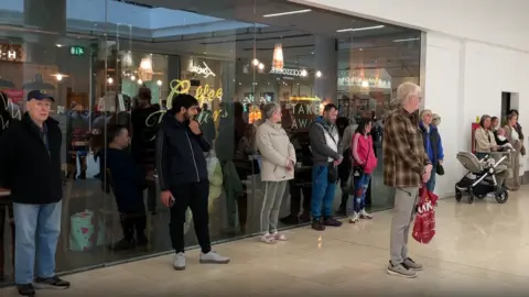 Shoppers in the Derbion Shopping Centre marking the two minute silence in memory of those who died in World War Two