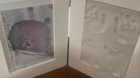 KATY MILLER A double frame containing a photograph of baby Oscar, and his hand and foot prints.