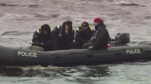 Four men on a police inflatable boat on the water