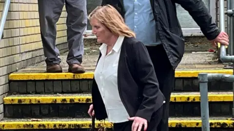 Bridget Curtis leaving court wearing a white shirt with a black jacket and skirt