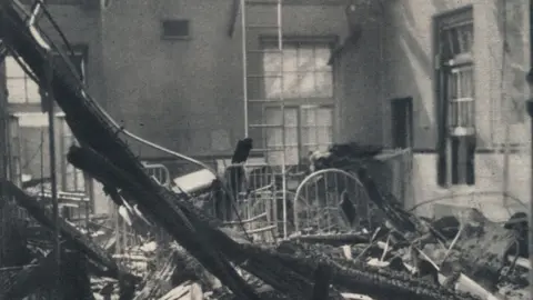 Getty Images A black and white archive photo showing rubble lying in a hospital ward. Beams from the roof are lying across thew floor. Beds are damaged. Debris is covering the floor. 